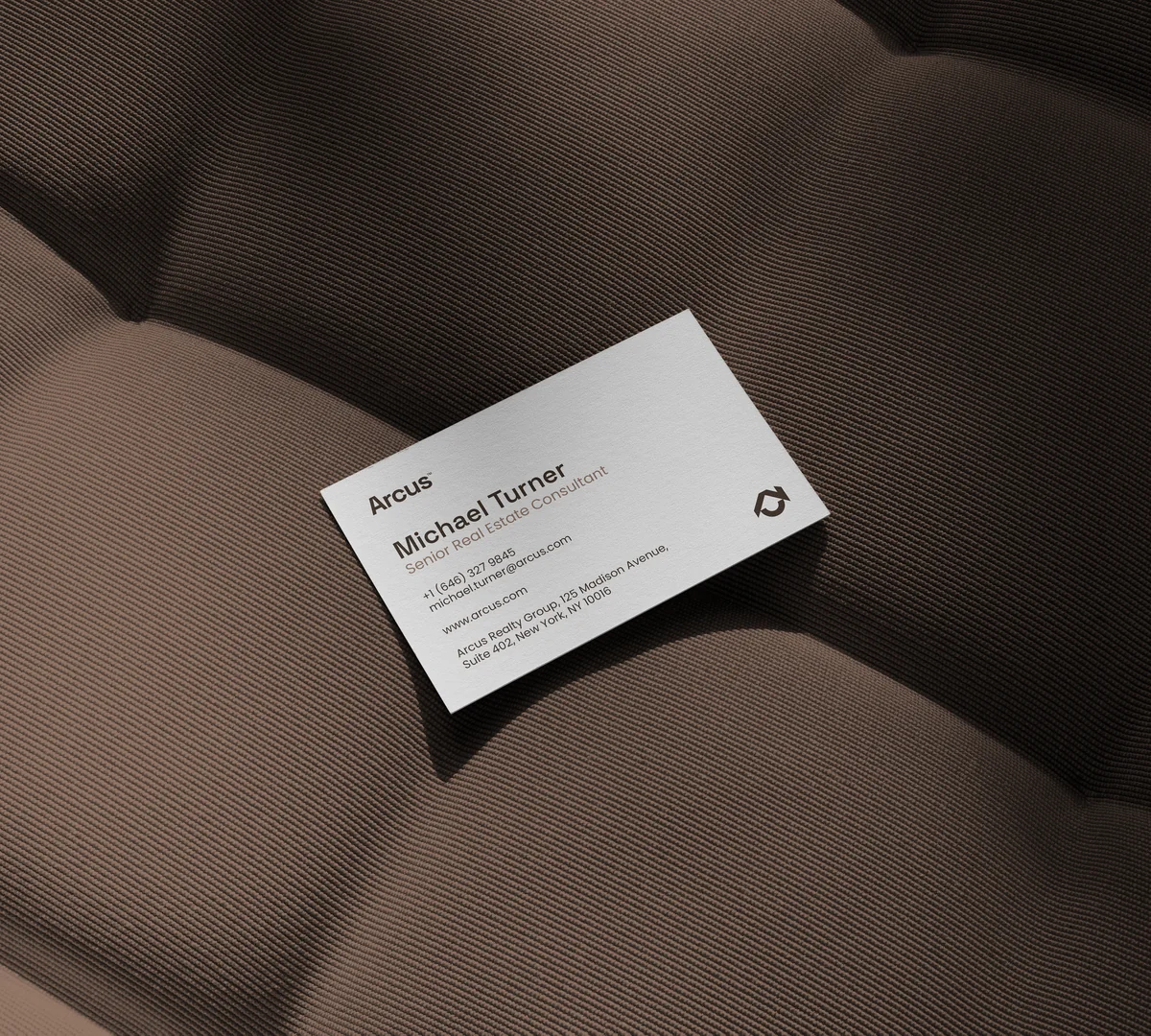The Arcus business card photographed on a dark textured surface